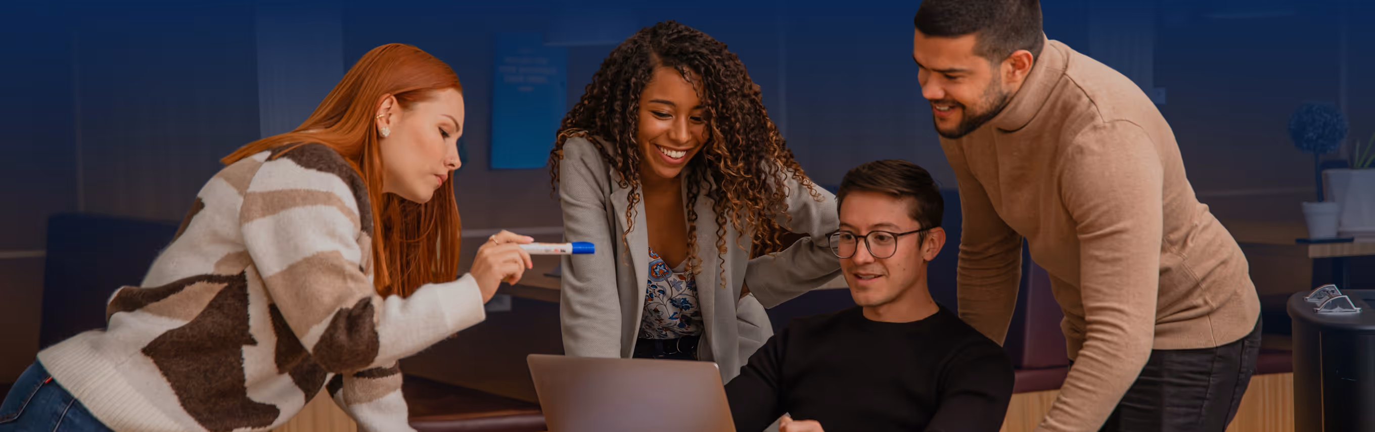 A group of people standing around a computer excited about what they are working on.